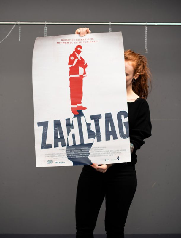 Photography of Nina Lesznik holding a poster of a production design project "Zahltag"