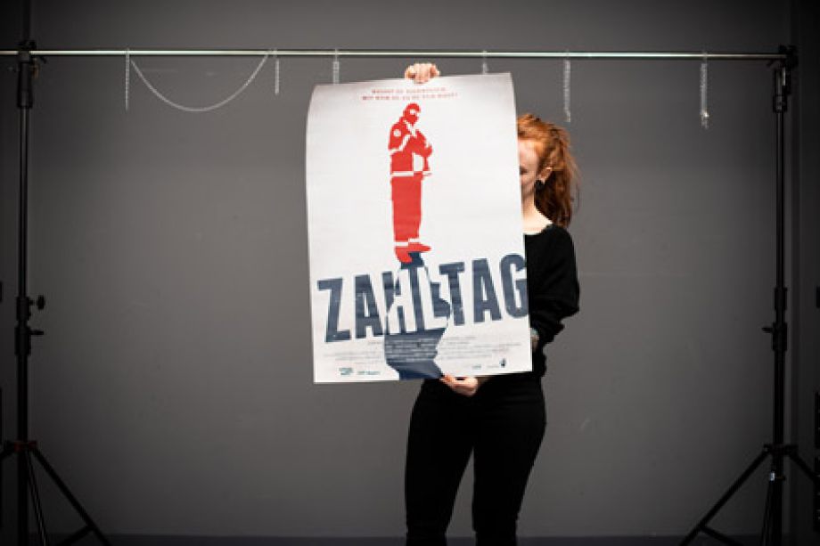 Photography of Nina Lesznik holding a large film poster of "Zahltag"