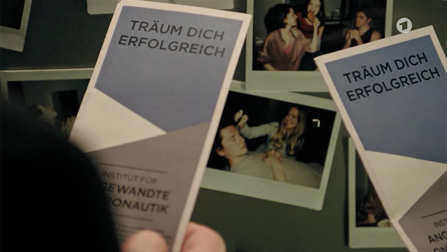 Screenshot from "Tatort Dreams" showing the main characters holding a brochure showing the oneironautics institute