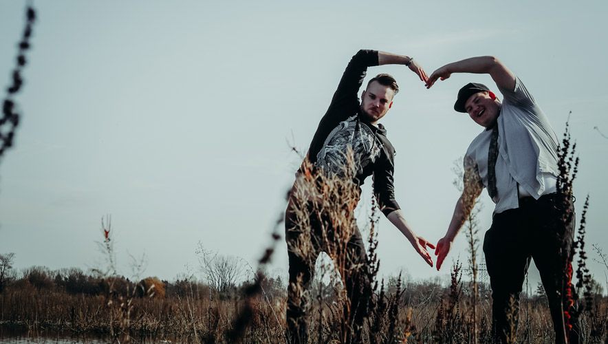 Photography of Deathcoustic Band members standing in a field shaping a heart with their arms